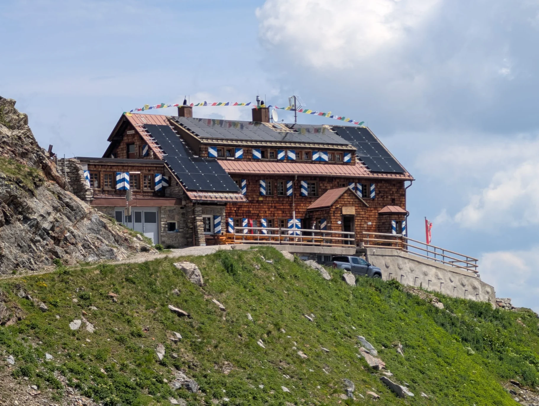 Die Saarbrücker Hütte mit Holzfassade, blau-weißen Fensterläden und Sonnenterrasse